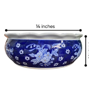 May include: A round ceramic bowl with a scalloped white rim and a deep blue exterior featuring a white floral pattern. The bowl measures 14 inches in width and 5 inches in height as indicated by the text and measurement lines in the image.