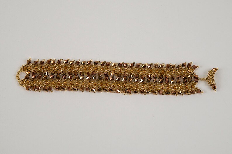 May include: A gold and brown beaded bracelet with a woven design. The bracelet has a clasp closure.