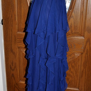 Puede incluir: Un vestido largo azul real sin tirantes con una falda con volantes en capas. El corpi&ntilde;o tiene un adorno de cuentas en la cintura. El vestido se exhibe en un maniqu&iacute;.