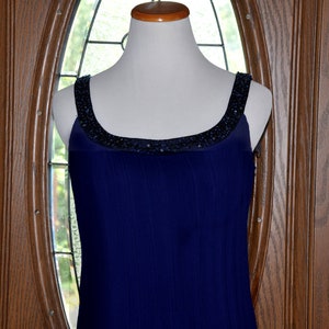 May include: A sleeveless navy blue dress with a beaded neckline.