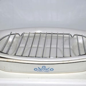 May include: White oval baking dish with a blue floral design and a metal rack inside.
