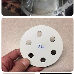 May include: White round disc with six holes and a green ring around the edge. The disc has a blue "M" written on it.