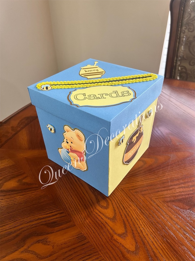 May include: A blue and yellow card box with a Winnie the Pooh character, a honey pot, and the word "Cards" on the top.