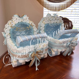 Puede incluir: Dos cochecitos de pastel de pa&ntilde;ales azul y blanco decorados con cinta dorada y la palabra "Bienvenido".