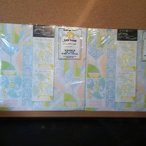 Puede incluir: Tres rollos de papel de regalo con patrones azules, verdes y rosas con el texto "Gift Wrap Wedding Gift" y "For Your Wedding" en el frente. Cada rollo contiene 2 hojas, 50,8 x 71,1 cm, para un total de 0,74 metros cuadrados.