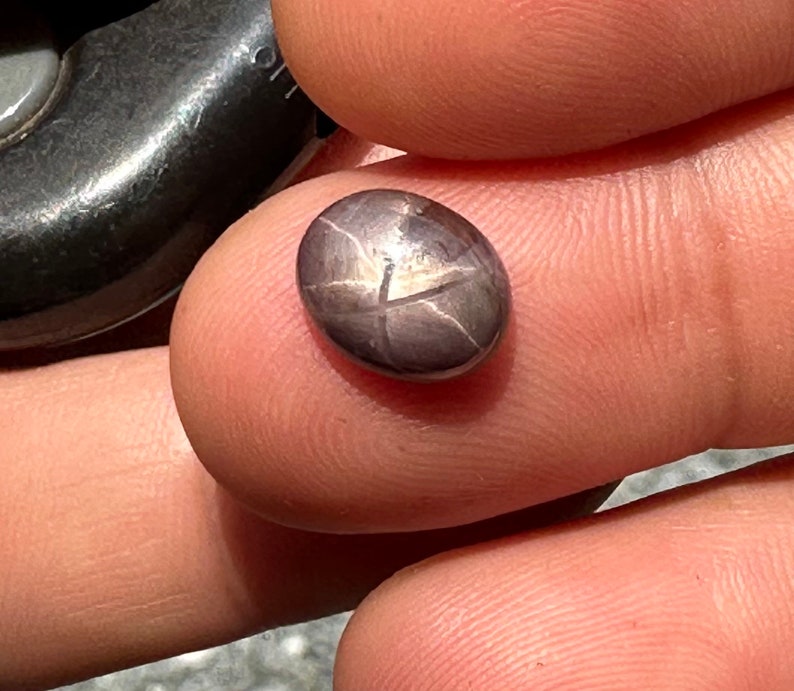May include: A dark gray star-shaped gemstone with a silver sheen.