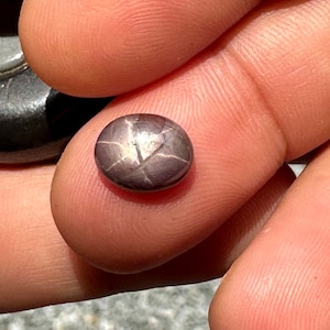 May include: A dark gray star-shaped gemstone with a silver sheen.