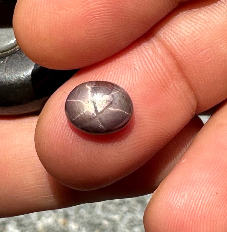 May include: A dark gray star-shaped gemstone with a silver sheen.