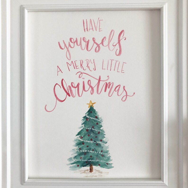 May include: A framed watercolour painting. The artwork displays the text "Have yourself a Merry Little Christmas" in pink script above a green Christmas tree decorated with red baubles and a gold star.