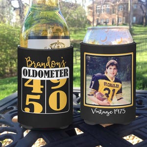 May include: Two black beverage insulators. One features the text "Brandon's OLDOMETER 49 50" in gold and white. The other displays a vintage photo and the text "Vintage 1975".
