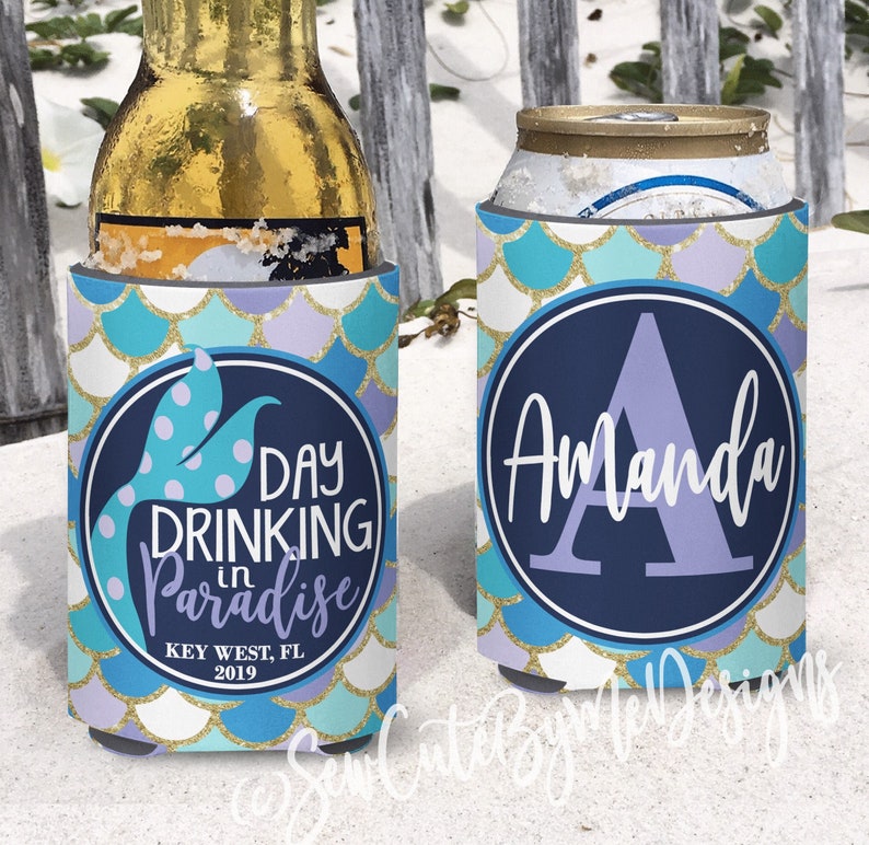 May include: Two blue and purple mermaid-themed can coolers. One cooler says "Day Drinking in Paradise Key West, FL 2019" with a mermaid tail. The other cooler has the letter "A" in a purple circle with the name "Amanda" written below it.