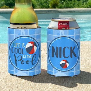May include: Two blue and white can coolers with a pool tile pattern. One cooler says "Life is Cool by the Pool" with a beach ball. The other cooler says "Nick" with a beach ball.
