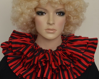 May include: A red and black striped ruffled collar, possibly for a costume, is shown on a mannequin. The collar is layered and has a striking design. The mannequin is wearing a black top and a blonde curly wig. The collar is likely for theatrical wear.