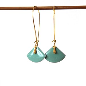 Peut inclure: Une paire de boucles d'oreilles pendantes dorées avec des breloques en forme d'éventail bleu sarcelle.
