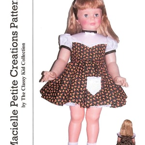 May include: A doll wearing a black dress with a pattern of orange and yellow shapes, a white bib, and white lace trim. The doll has blonde hair and is wearing black shoes and white socks. The text "Macielle Petite Creations Pattern" is visible.