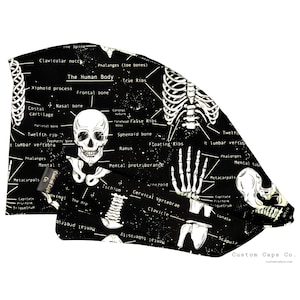 Könnte beinhalten: Schwarz-weißes Stoffmuster mit einem sich wiederholenden Muster aus einem Skelett, Knochen und anatomischen Beschriftungen. Der Stoff trägt den Text "The Human Body" und "Custom Caps Co."
