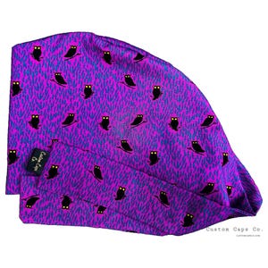 Peut inclure: Un bonnet de chirurgien violet avec un motif répété de hiboux noirs perchés sur des branches. Le fond présente un motif texturé bleu et violet. Le bonnet porte une petite étiquette noire avec le texte blanc "Custom Caps Co."