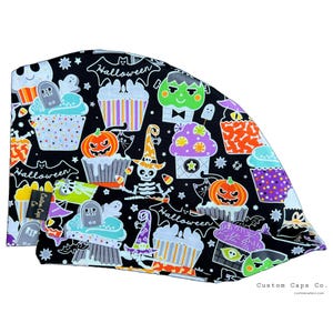 May include: Black surgical cap with a Halloween-themed pattern. The design features cupcakes, pumpkins, skeletons, and the word "Halloween" in white. The cap is made of a soft, patterned fabric.