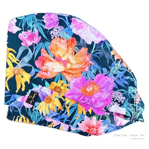 Puede incluir: Un gorro de quirófano azul verdoso con estampado floral con flores rosas, naranjas y amarillas. El gorro tiene una pequeña etiqueta negra con el texto "Custom Caps Co."