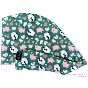 May include: A green scrub cap featuring a repeating pattern of farm animals: pink pigs, white sheep, brown rabbits, and white chickens. The cap includes a matching headband. The text "Custom Caps Co." is visible.