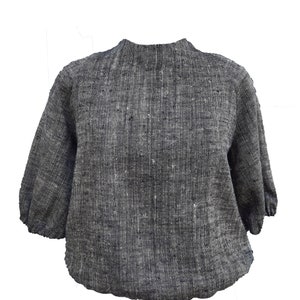 May include: A gray linen blouse with a round neckline and 3/4 sleeves. The blouse has a slightly puffed sleeve and a relaxed fit.