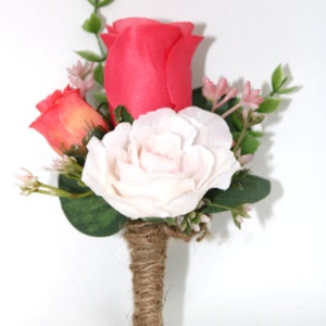 May include: A small bouquet of artificial flowers with a pink rose, a coral rose, and a white rose. The bouquet is tied together with twine.