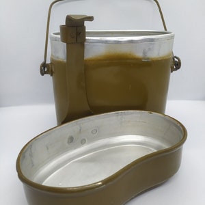 May include: A green metal camping mess kit with a handle and a separate bowl. The kit is made of aluminum and has a green enamel finish.