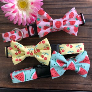 May include: Three dog collars with matching bow ties. The collars are pink, yellow, and blue with a strawberry, cherry, and watermelon print. The bow ties are made of the same fabric as the collars.