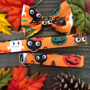 May include: Orange and black Halloween-themed dog collar and leash set with a bow tie. The fabric features a repeating pattern of ghosts, black cats, pumpkins, and owls.