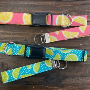 May include: Three dog collars with lemon print fabric. The collars are in pink, blue and green with white polka dots. The collars have black buckles and silver rings.