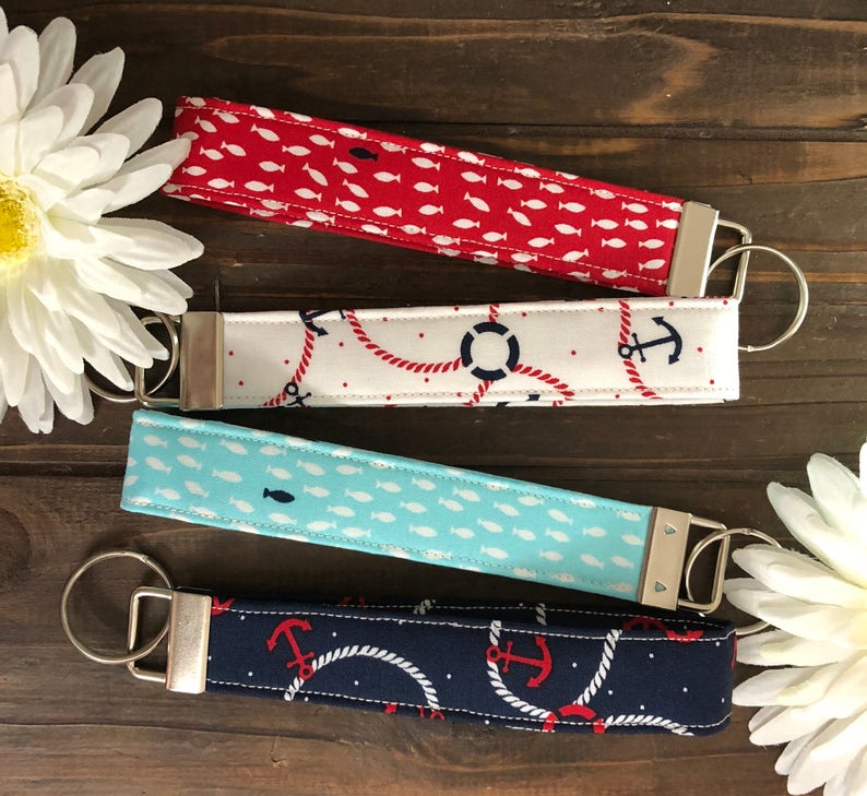 May include: Four fabric key fobs with metal hardware. The key fobs feature nautical patterns: red with white fish, white with red rope and navy anchors, light blue with white fish, and navy with red anchors and white rope.