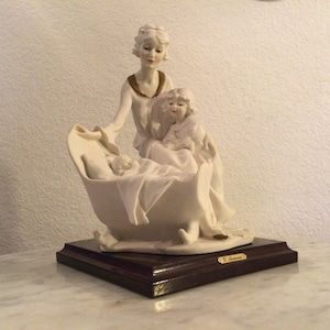 GIUSEPPE ARMANI FLORENCE “A New Arrival” Porcelain Sculpture. Mother&Daughter Rocking A Baby’s Cradle. White,Gold Details. Signed.From 1990.