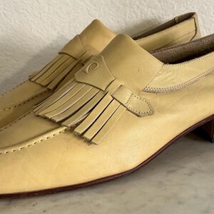 Puede incluir: Un par de mocasines de cuero amarillo claro con detalle de borlas. Los zapatos tienen un tac&oacute;n bajo y una punta redondeada. Los mocasines son un estilo cl&aacute;sico, adecuado para diversas ocasiones.