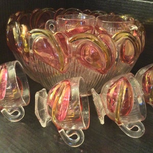 Peut inclure: Un ensemble de saladier à punch en verre vintage avec un saladier en verre transparent et six tasses. Le saladier et les tasses ont un motif en spirale rose et or.