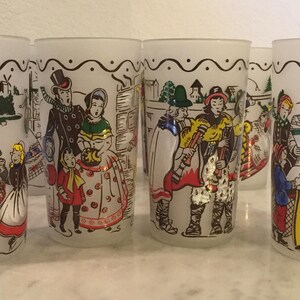 K&ouml;nnte beinhalten: Satz von sechs klaren Glasbechern mit bunten Illustrationen von Menschen in Winterszenen. Die Illustrationen zeigen Menschen mit M&uuml;tzen und M&auml;nteln, einige halten Musikinstrumente.