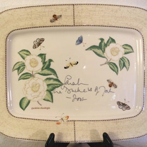 Puede incluir: Un plato de servir de cer&aacute;mica blanca con un dise&ntilde;o floral con camelias blancas y hojas verdes. El plato tiene un borde marr&oacute;n con un dise&ntilde;o de cuerda. El texto "Sarah The Duchess of York - 2001" est&aacute; escrito con tinta negra en el plato.