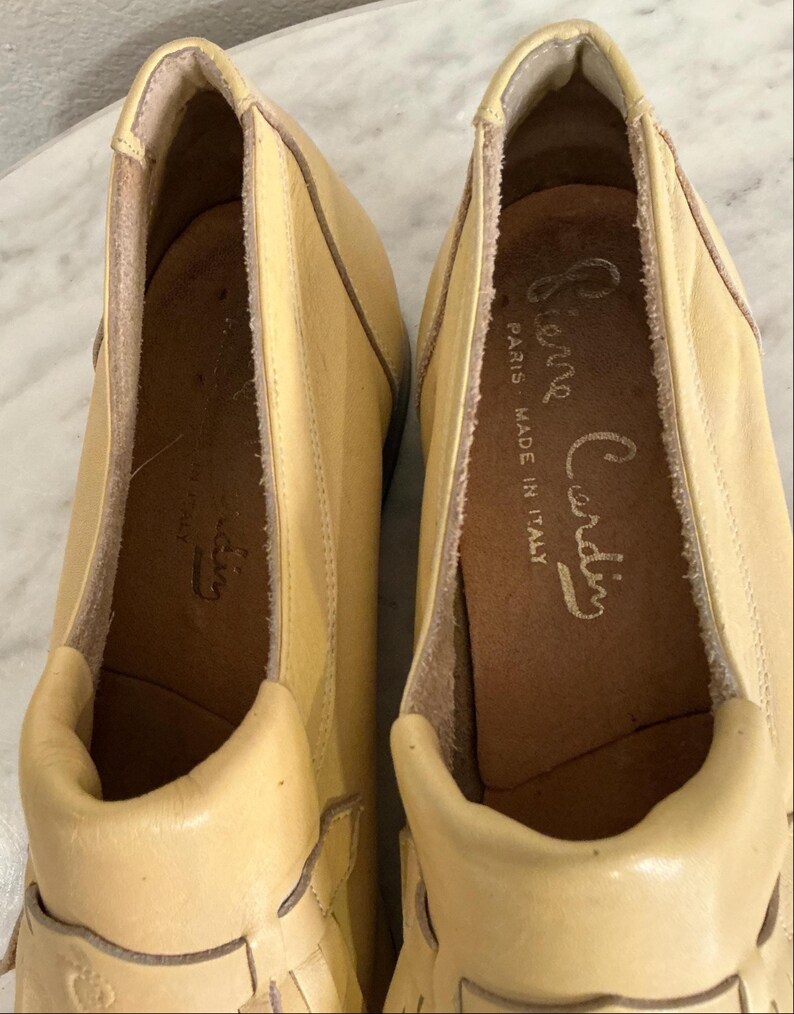 Puede incluir: Un par de mocasines Pierre Cardin de color amarillo claro. Los zapatos son de cuero y tienen una puntera redondeada y un tac&oacute;n bajo. El interior del zapato est&aacute; estampado con el logotipo de Pierre Cardin y "Paris Made in Italy".