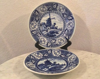 Dos platos decorativos de pared vintage de cerámica BOCH "DELFTS" con forma de molino de viento. Blanco y azul, con borde de flores y hojas. Hecho en Holanda.