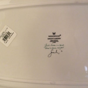Puede incluir: Plato de cer&aacute;mica blanco con una etiqueta Wedgwood Sarah's Garden Edici&oacute;n Especial. La etiqueta incluye el texto "Sarah's Garden is a special place to dream and grow." y una firma.