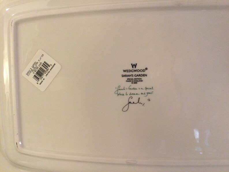 Puede incluir: Plato de cer&aacute;mica blanco con una etiqueta Wedgwood Sarah's Garden Edici&oacute;n Especial. La etiqueta incluye el texto "Sarah's Garden is a special place to dream and grow." y una firma.