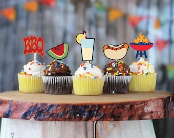 May include: Six cupcakes decorated with colorful sprinkles and various summer-themed toppers, including a watermelon slice, a glass of lemonade, a hot dog, a grill, and the word "BBQ".