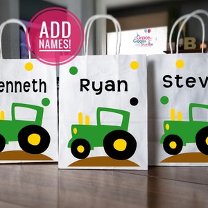 May include: Three white paper gift bags with green and yellow tractor designs and the names Kenneth, Ryan, and Steve printed on them.