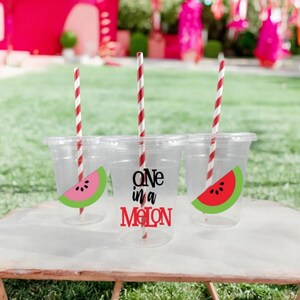 May include: Three clear plastic cups with red and white striped straws. Each cup has a watermelon slice sticker with the text "One in a Melon" on one cup.