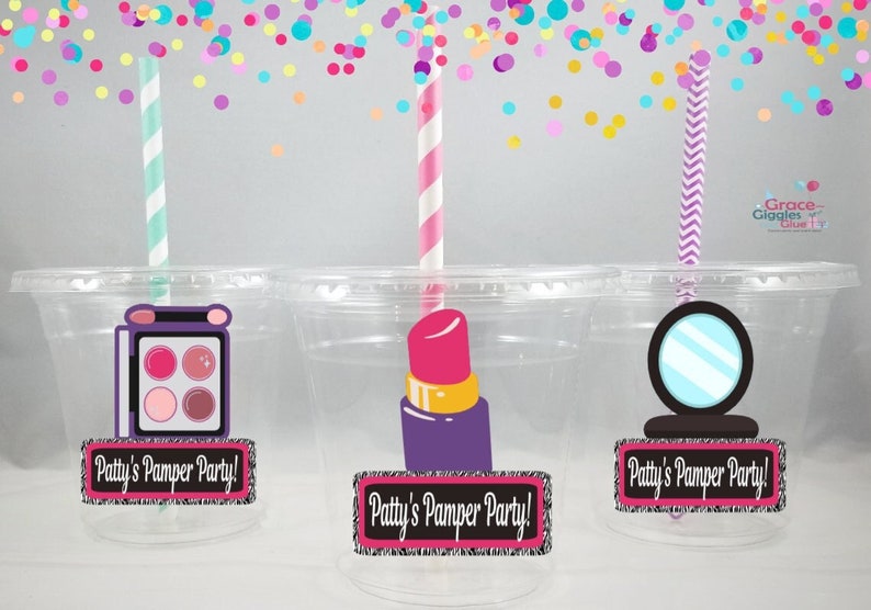 May include: Three clear plastic cups with straws and colorful confetti falling from above. Each cup has a different makeup-themed design: an eyeshadow palette, lipstick, and a mirror. Each cup has a label that reads "Patty's Pamper Party!"
