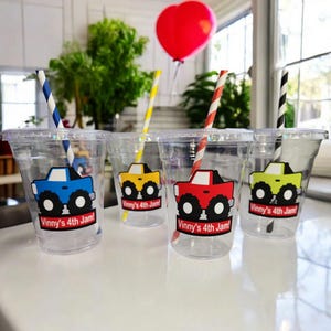 May include: Four clear plastic cups with colorful monster truck designs and the text "Vinny's 4th Jam!" on each cup. Each cup has a striped straw.