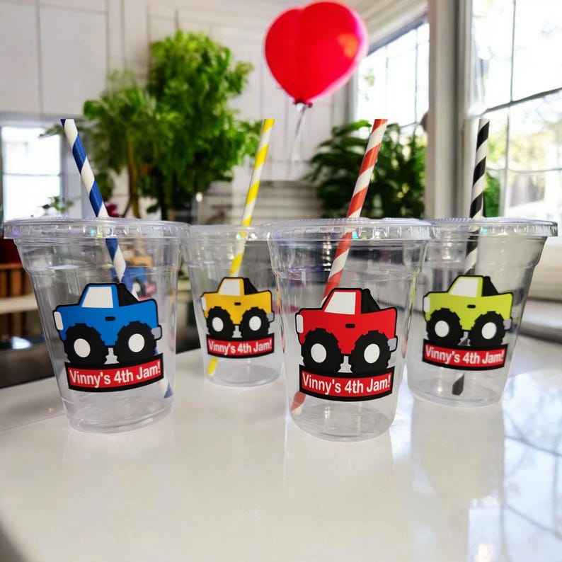 May include: Four clear plastic cups with colorful monster truck designs and the text "Vinny's 4th Jam!" on each cup. Each cup has a striped straw.