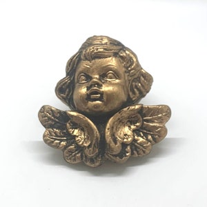 May include: A gold cherub figurine with wings. The cherub has a sweet expression on its face.