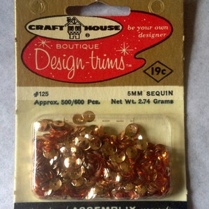 May include: A package of gold 5mm sequins, labeled "Craft House Boutique Design-Trims" with the number 125, approximately 500-600 pieces, and a net weight of 2.74 grams. The package is labeled "19c".
