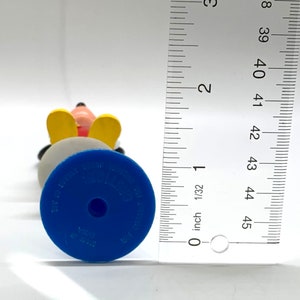 May include: A blue and yellow plastic figurine of Mickey Mouse. The figurine is about 4 inches tall and has a blue base with the words "Disney Store" and "Made in China" printed on it.