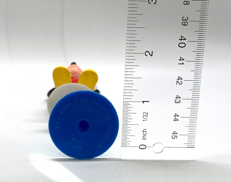 May include: A blue and yellow plastic figurine of Mickey Mouse. The figurine is about 4 inches tall and has a blue base with the words "Disney Store" and "Made in China" printed on it.